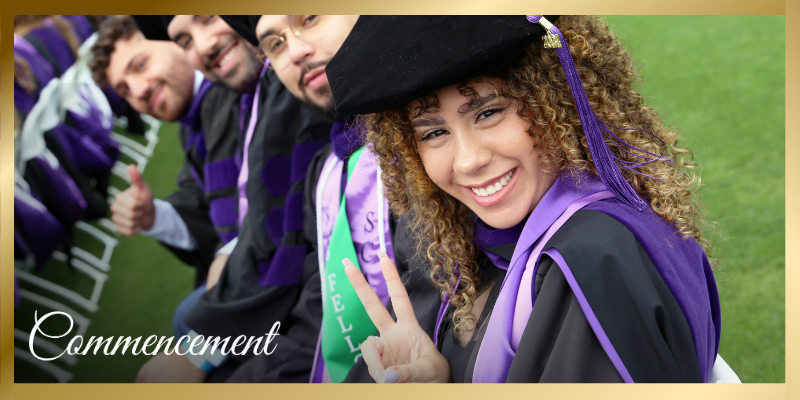 Row of Southwestern graduates in regalia smiling at camera with girl in front holding peace finger sign