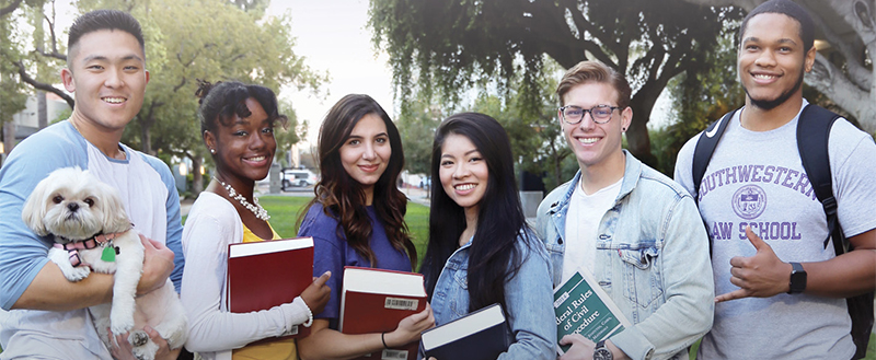 Image - Group of Southwestern students holding books and dog on promenade lawn