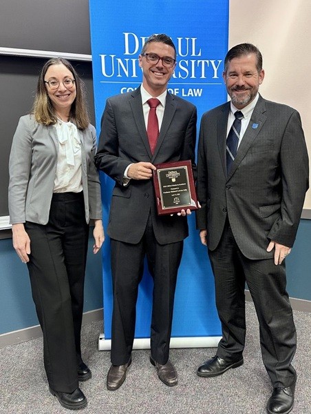 Prof. Richard Jolly smiling with his award and two others at DuPaul University 