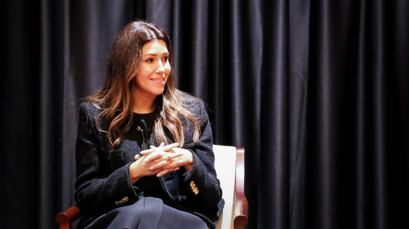 Camille Vasquez '10 sitting at speaking event in front of black curtains