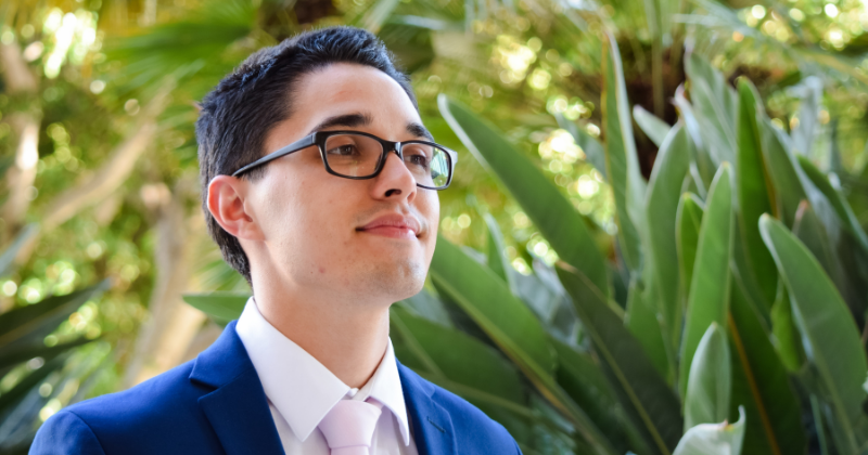 Close up of Chris Phelps in glasses and dark blue suit looking into the distance